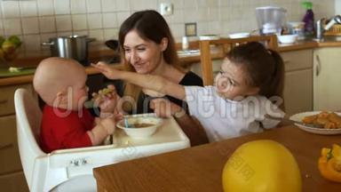 年轻的妇女家庭主妇在<strong>厨房</strong>里喂两个孩子。 <strong>幼儿</strong>和学龄前女孩